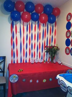 a table with red, white and blue balloons on it in front of a wall