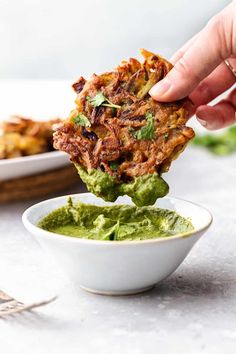 a person dipping guacamole into a small white bowl filled with guacamole