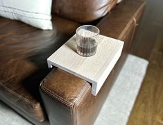 a glass sitting on top of a wooden table next to a brown leather couch in a living room