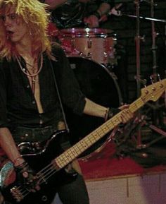 a woman with blonde hair playing a bass guitar