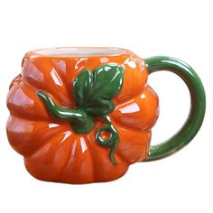 an orange ceramic pumpkin mug with green handles