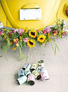 the flowers are sitting on the ground next to some tin cans and a yellow vw bug