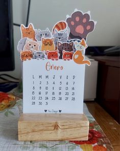 a calendar with cats on it sitting on top of a wooden stand in front of a computer monitor