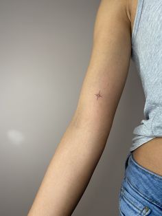 a woman's arm with a tiny star tattoo on the left side of her arm