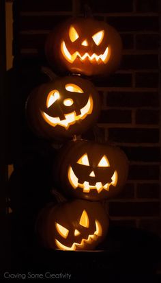 three jack o lantern pumpkins sitting on top of each other in front of a brick wall