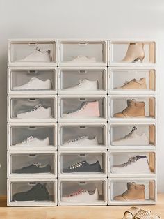 a stack of clear drawers filled with pairs of shoes on top of a wooden table