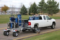 a white truck with an air compressor attached to it's flatbed is driving down the road