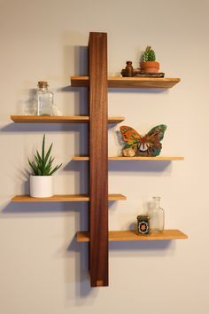 three wooden shelves with plants and other items on them in the corner of a room