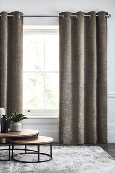 a living room with two coffee tables and curtains