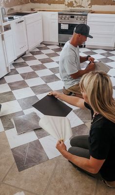 two people sitting on the floor in a kitchen working on some tile work with tools