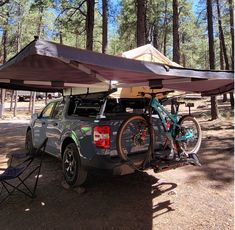 a truck with two bikes on the back parked under a awning over it's cargo area