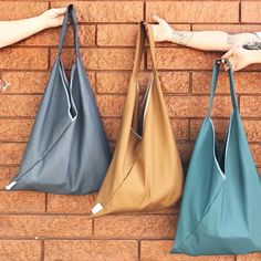 three different colored bags hanging on a brick wall