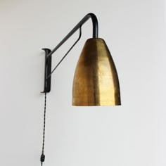 a wall mounted light with a long arm and a gold shade on the back of it