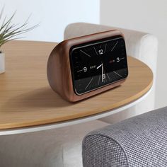 an alarm clock sitting on top of a wooden table next to a potted plant