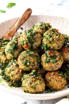 a white bowl filled with meatballs covered in pesto