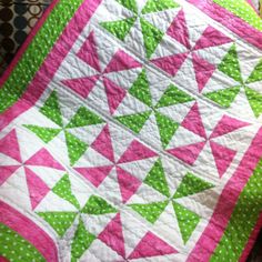 a pink and green quilt on top of a bed