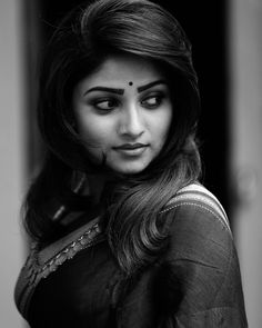 black and white photo of a woman with long hair wearing a sari, looking at the camera