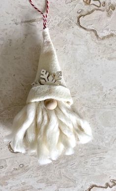 a gnome ornament hanging from a string on a white tablecloth covered surface