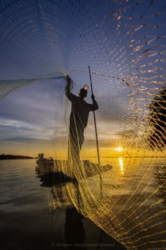 a man standing on top of a body of water holding a fishing net over his head