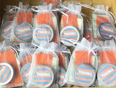 a box filled with lots of orange and white treats in plastic bags on top of a wooden table