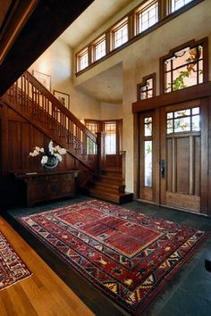 an entryway with stairs and rugs on the floor in front of wooden doors