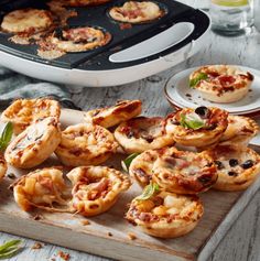 mini pizzas are sitting on a cutting board