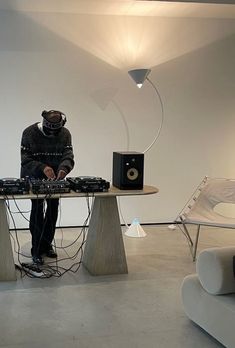 a person sitting at a table with some electronic equipment on it and a speaker in front of them