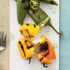 grilled peppers on a plate next to a fork and knife