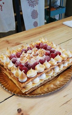 two desserts sitting on top of a wooden table next to each other with strawberries and whipped cream