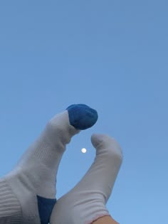 a person's hand with white and blue gloves holding a cell phone up to the sky