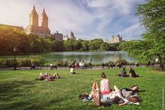 people are sitting on the grass near a lake in central park, new york city