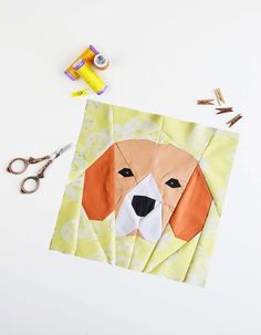 a paper cut out of a dog's face with scissors and thread next to it