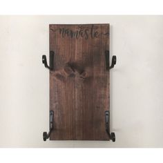 a wooden sign that says namistee on it with two black hooks hanging from the wall