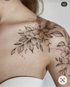 a woman's shoulder with flowers and leaves tattooed on her chest, in black ink