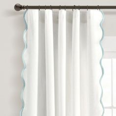 white curtains with scalloped edges hanging on a curtain rod