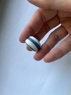 a person's hand with a blue and white striped ring on their thumb,