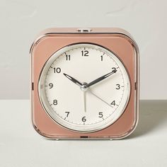 an alarm clock is sitting on a white surface with black hands and two sides are visible