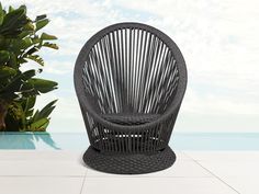 a black wicker chair sitting on top of a white tile floor next to a pool