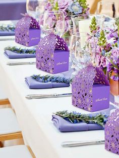 the table is set with purple napkins and place settings for guests to sit at