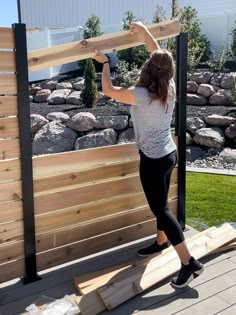 a woman is building a wooden fence outside