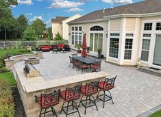 an outdoor patio with tables and chairs next to a fire pit in the middle of it