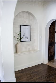 a white room with wood floors and an arched doorway