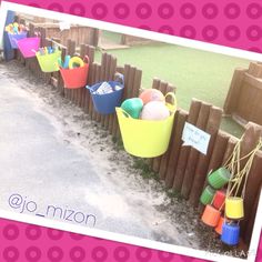 there are many buckets on the side of this fence with name tags attached to them