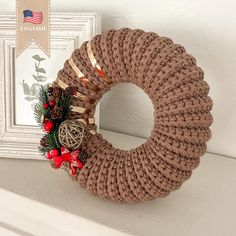 a wreath is hanging on the mantle next to a framed photo and an ornament