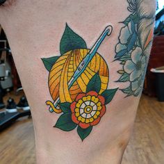 a woman's leg with a tattoo on it that has a flower and a knitting needle