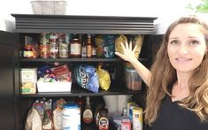 a woman standing in front of an open refrigerator with lots of food on the shelves