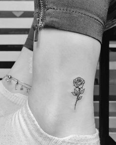 a small rose tattoo on the side of a woman's ankle, with a zipper at the bottom