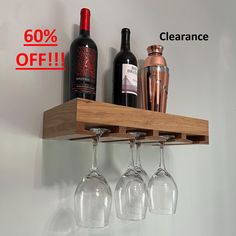 three wine glasses are hanging on a shelf with the sale sign in front of them