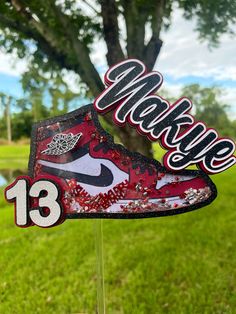 a pair of sneakers with the number thirteen painted on them sitting in front of a tree