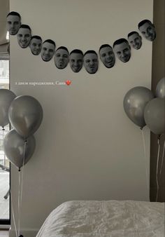 some balloons are hanging on the wall in front of a bed with pictures of people